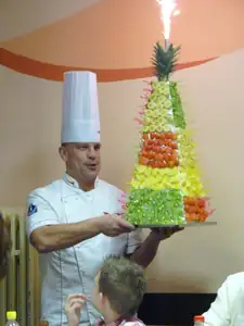 pan šéfkuchař nás zve na čokoládovou fontánu a k tomu nese pyramidu s kousky ovoce...