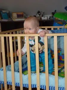 Adámek se už sám postaví v postýlce...